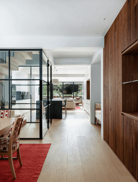 Modern open-plan interior with glass partitions, wooden accents, and natural light from large windows.