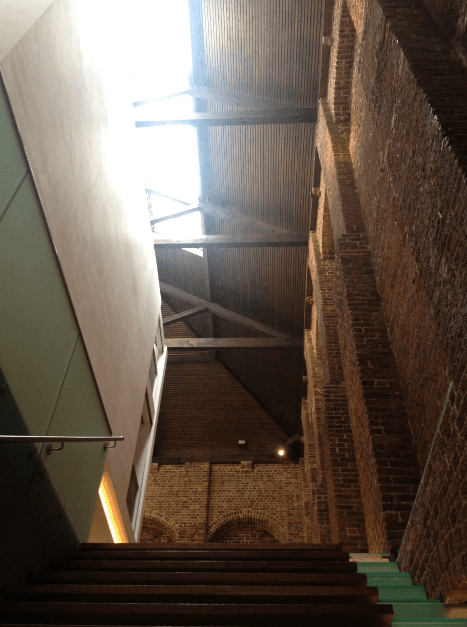 Interior view of a historic brick building with modern renovation, showing a high ceiling and wooden beams.